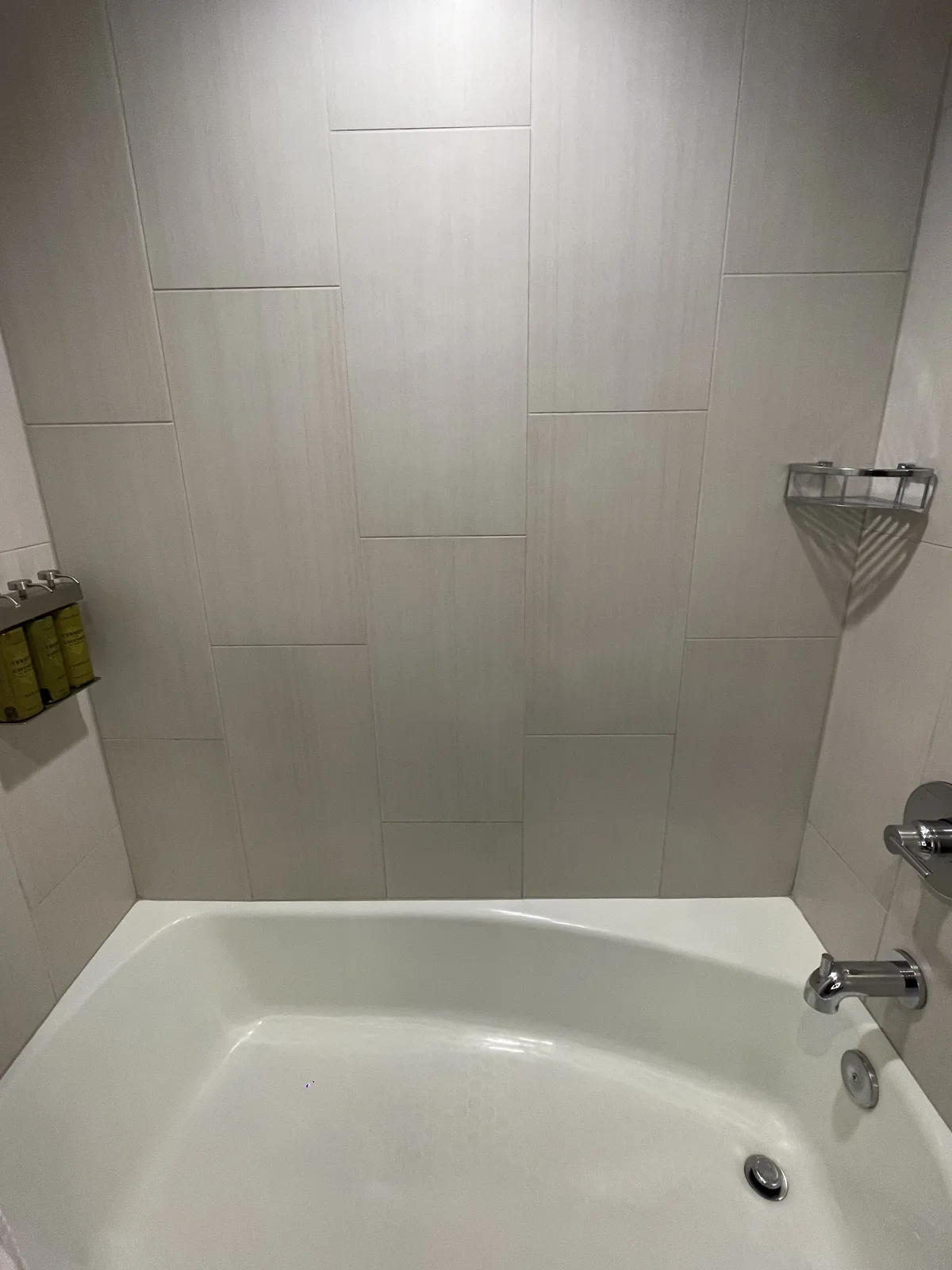 Hilton Seattle bathroom with combination bathtub and shower, white tiles, and wall-mounted toiletry dispensers